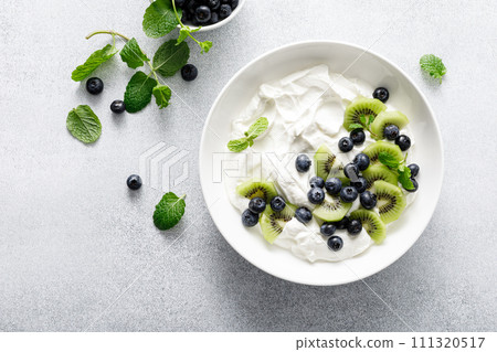 White plain greek yogurt with fresh blueberries and kiwi fruit, top view 111320517