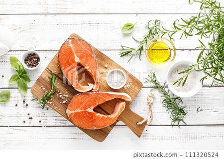 Fresh raw salmon steaks on a board with ingredients for cooking, top view Fresh raw salmon steaks on a board with ingredients for cooking, top view 111320524
