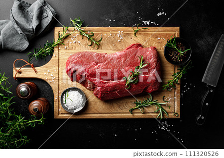 Beef meat entrecote on a cutting board, raw beef meat fillet on black background, top view Beef meat entrecote on a cutting board, raw beef meat fillet on black background, top view 111320526
