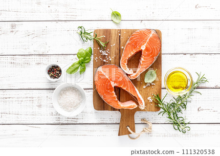 Fresh raw salmon steaks on a board with ingredients for cooking, top view Fresh raw salmon steaks on a board with ingredients for cooking, top view 111320538