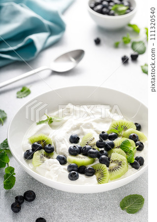 White plain greek yogurt with fresh blueberries and kiwi fruit White plain greek yogurt with fresh blueberries and kiwi fruit 111320540