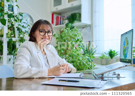 Portrait of mature woman working at home on computer laptop Portrait of mature woman working at home on computer laptop 111320565