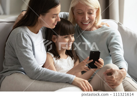 Happy little girl with mother and grandmother using smartphone together Happy little girl with mother and grandmother using smartphone together 111321614