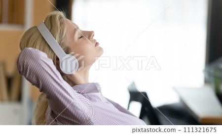 Calm young woman listen to music in headphones Calm young woman listen to music in headphones 111321675