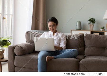 Attractive Indian woman sit on sofa with laptop Attractive Indian woman sit on sofa with laptop 111321850