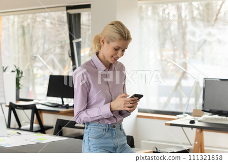 Smiling female employee use cellphone texting online Smiling female employee use cellphone texting online 111321858