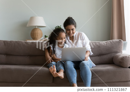 Indian woman and daughter sit on sofa with laptop 111321867