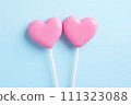 AI-generated content. Two pink heart-shaped lollipops on blue. 111323088