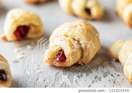 Homemade bagel cookies with dried fruits and walnuts on gray background close up. Sweet croissant cookies 111323354