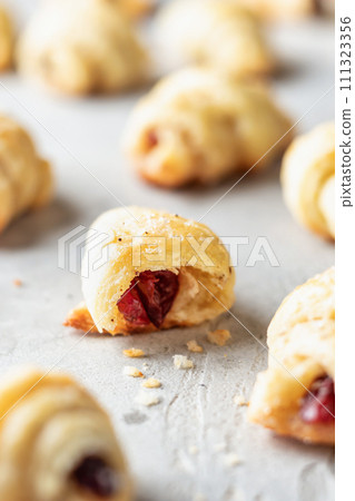 Homemade bagel cookies with dried fruits and walnuts on gray background close up. Sweet croissant cookies Homemade bagel cookies with dried fruits and walnuts on gray background close up. Sweet croissant cookies 111323356