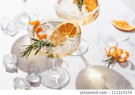Two sidecar cocktails with sugar rims on white marble table. Festive party composition 111323374