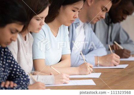 Multiracial students in row writing exam on paper 111323568