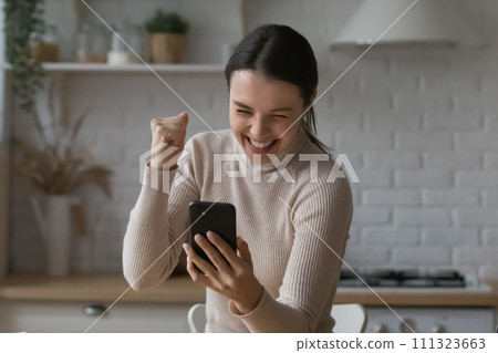 Woman holds smartphone read sms celebrate fantastic news looks overjoyed 111323663