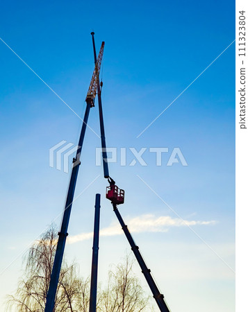 Installing the antenna on a blue sky background. Worker connects two metal pipes. 111323804