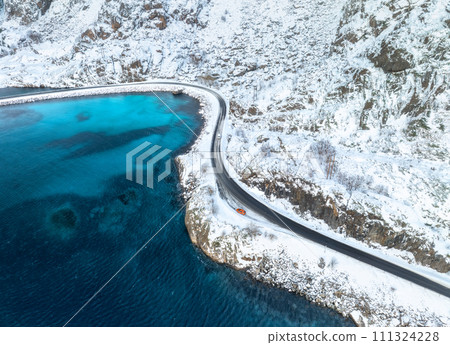 Aerial view of curved snowy road to the island and blue sea 111324228