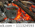 Touristic bowler on burning coals. Cooking hot drinks from the hips and forest berries on the touristic fire. 111324593