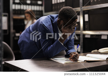 African american inspector thinking at ideas to solve criminal case, analyzing investigation report. Private detective searching for criminology evidence, working overtime in arhive room. African american inspector thinking at ideas to solve criminal case, analyzing investigation report. Private detective searching for criminology evidence, working overtime in arhive room. 111325044