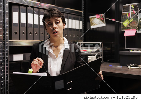 Private investigator discussing with remote police officer during videocall meeting conference, working late at night at criminal case report in evidence room. Online discussion concept 111325193