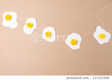 simple fried eggs paper craft hanging from a string, easter decoration concept, top view 111325366