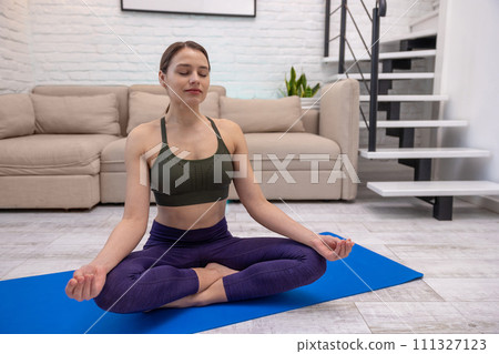 Cute young yogini meditating in lotus pose Cute young yogini meditating in lotus pose 111327123