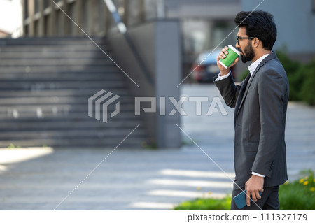 Young businessman having coffee outside and feeling good 111327179