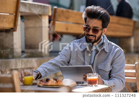 Dark-haired hindu man eating pizza and working on laptop Dark-haired hindu man eating pizza and working on laptop 111327248