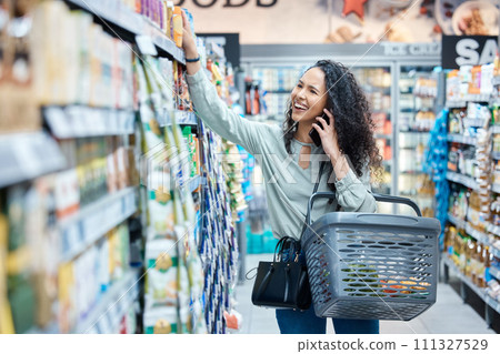Shopping, phone call and happy woman in a grocery aisle while browsing and choosing products in supermarket, store or shop. Laugh, consumerism and communication while calling and holding food basket Shopping, phone call and happy woman in a grocery aisle while browsing and choosing products in supermarket, store or shop. Laugh, consumerism and communication while calling and holding food basket 111327529