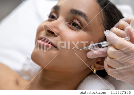 Young dark-skinned woman having a session of mesotherapy Young dark-skinned woman having a session of mesotherapy 111327596