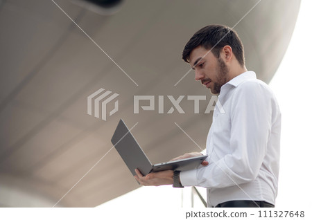Young businessman with a phone in hand looking confident Young businessman with a phone in hand looking confident 111327648