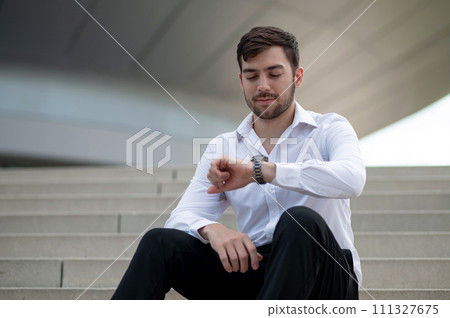 Confident young man in white shirt sitting on the steps 111327675