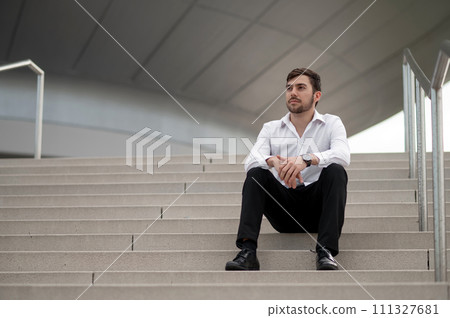 Confident young man in white shirt sitting on the steps 111327681