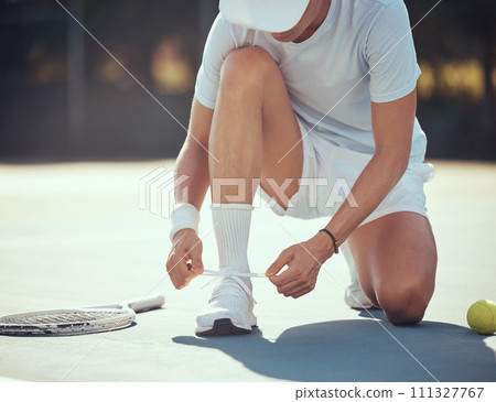 Exercise, tennis and a man tying his shoes on a court before a match. Summer fitness, sport training and healthy lifestyle with tennis ball and sneakers. Motivation, workout and a knot in a shoe lace Exercise, tennis and a man tying his shoes on a court before a match. Summer fitness, sport training and healthy lifestyle with tennis ball and sneakers. Motivation, workout and a knot in a shoe lace 111327767