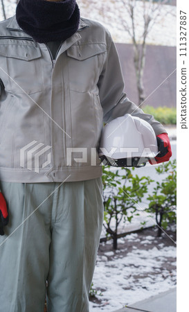 在雪景中，一名穿著工作服的男子使用頸部保暖器來保護自己免受寒冷 111327887