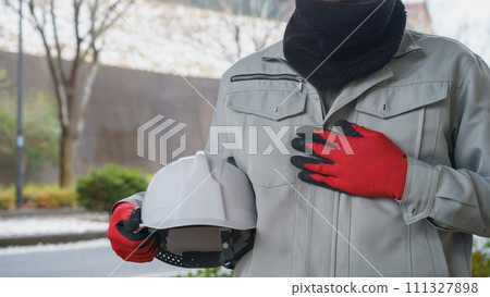 在雪景中，一名穿著工作服的男子使用頸部保暖器來保護自己免受寒冷 111327898