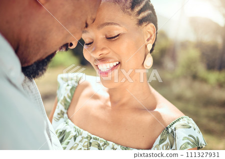 Love, black couple and forehead touch in nature with a smile on holiday or date. Happy black man and woman, romantic African people or lovers bonding in affection together in the shining summer sun. Love, black couple and forehead touch in nature with a smile on holiday or date. Happy black man and woman, romantic African people or lovers bonding in affection together in the shining summer sun. 111327931