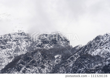 Mountain covered with snow and fog. Alpine landscape in Italy, Europe. Snow-capped mountains 111328116