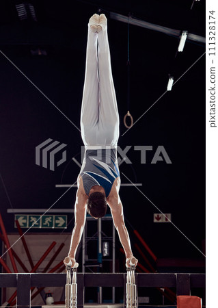 Strong man training for fitness in gym, cardio sports exercise at stadium at night and sport workout for health and wellness in dark arena. Young athlete person doing gymnastics in competition 111328174