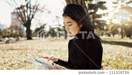 Japanese woman, reading and book on lawn, thinking and relax by tree, park or sunshine with peace. Girl, person or student with story in nature, college or idea with vision, knowledge or campus grass 111329739