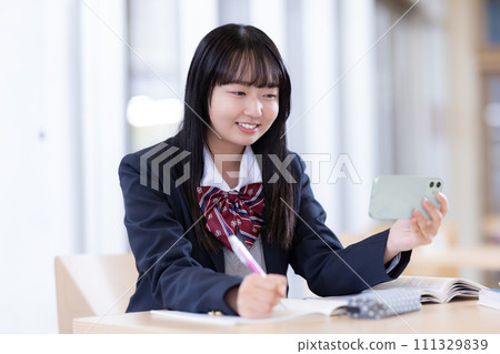High school girl studying while looking at her smartphone Photography cooperation: Ariake College of Education and Arts High school girl studying while looking at her smartphone Photography cooperation: Ariake College of Education and Arts 111329839