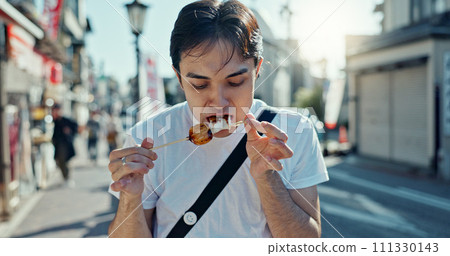 Man, street food and eating kebab on walk on travel, city and hungry for goheimochi with nutrition, diet or lunch. Person, rice snack and skewer on metro sidewalk, vacation and urban road in Japan 111330143