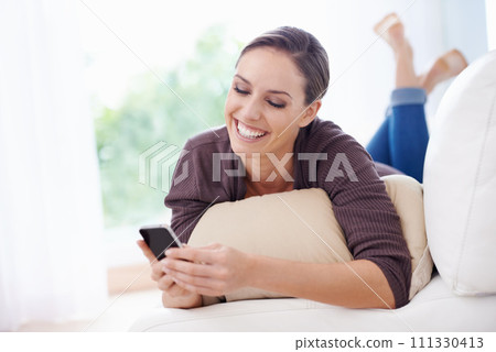 Happy, woman and phone for typing on sofa, scroll social media and reading chat notification in lounge at home. Lady, relaxing and download digital app, mobile games and search contact on smartphone 111330413