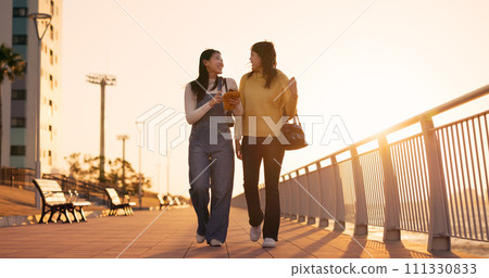 Walking, women and friends with smartphone, outdoor and happiness with social media, connection and sunshine. People, Japan or girls with cellphone, mobile user and funny with network or digital app 111330833