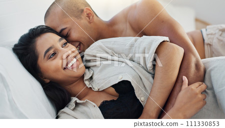Happy couple, relax and kissing on bed for embrace, love or morning romance in trust or care at home. Young man and woman smile lying in bedroom hug for intimacy, passion or bonding together at house 111330853