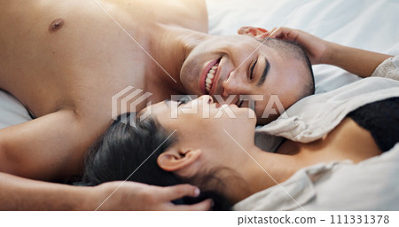 Happy couple, talking in bed with love, intimacy and romance at home for relationship, sex and bonding. Young people, woman and man relax in bedroom with gentle touch and kiss for valentines day 111331378