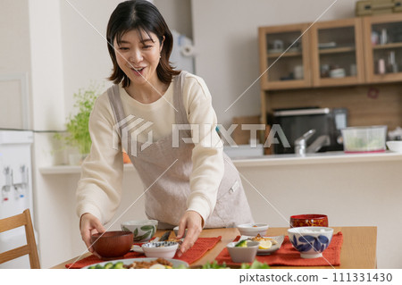 A woman cooking/serving a meal/a smiling housewife A woman cooking/serving a meal/a smiling housewife 111331430