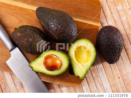 Whole and sliced avocados on wooden board Whole and sliced avocados on wooden board 111331978