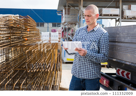 Worker prepares metal rebar for loading onto truck 111332009