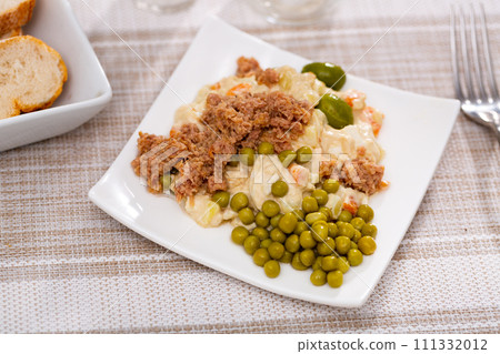 Ensalada rusa - salad with potatoes, tuna, green pea, olives and egg in plate 111332012