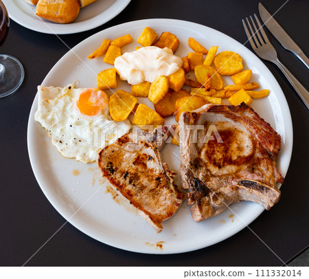 Close-up of Spanish hearty breakfast with pork, potatoes and egg 111332014