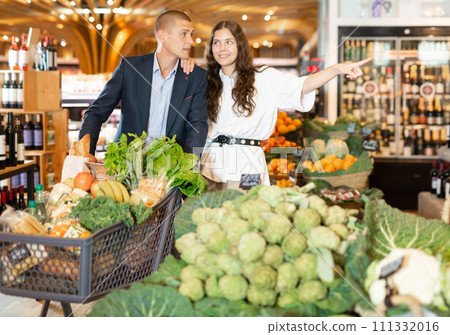 Portrait of a happy young couple in a supermarket with a full grocery cart 111332016